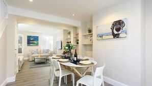 Un coin repas avec une table ronde, des chaises blanches et un tableau représentant un chien accroché au mur.