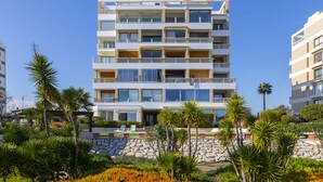 A multi-story hotel with balconies, large windows, and a stone facade. - Mackenzie Castella Beachfront Suite (Larnaca)