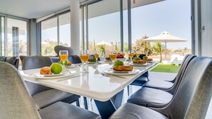 A dining area with a table set for breakfast, large windows, and a view of the outdoors.