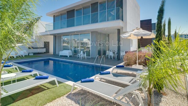 A modern two-story house with a swimming pool, outdoor seating, and a covered patio area.