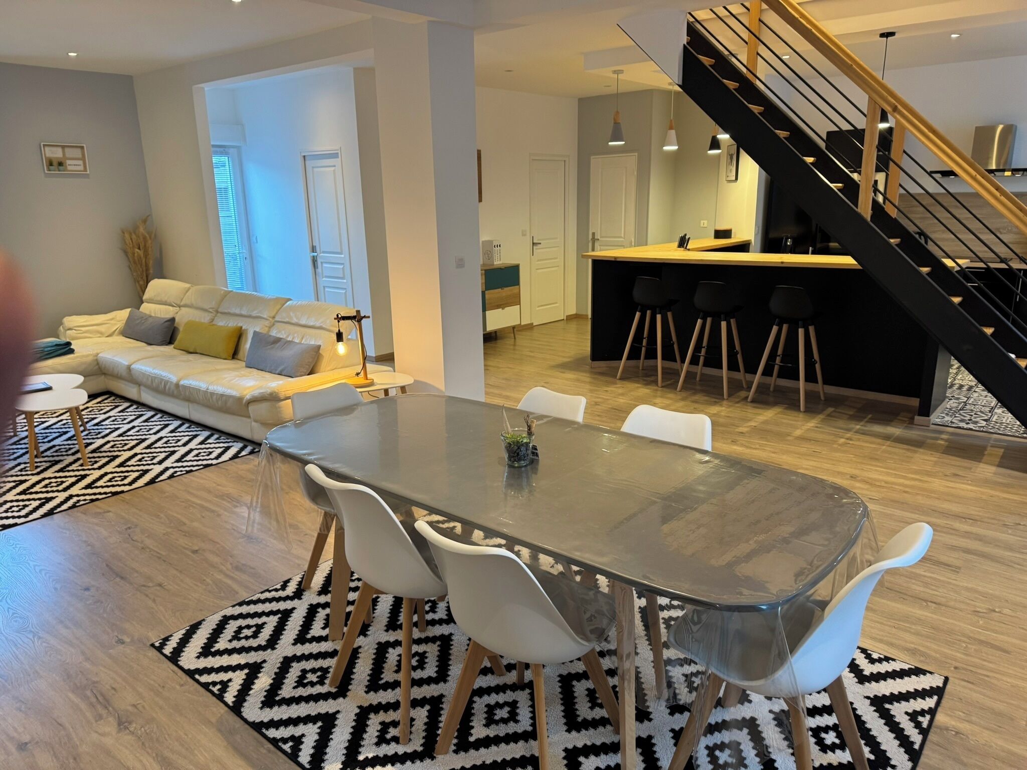 Ein moderner Wohnbereich mit Essplatz, einer Couch, einer Treppe und einer Küchenzeile.