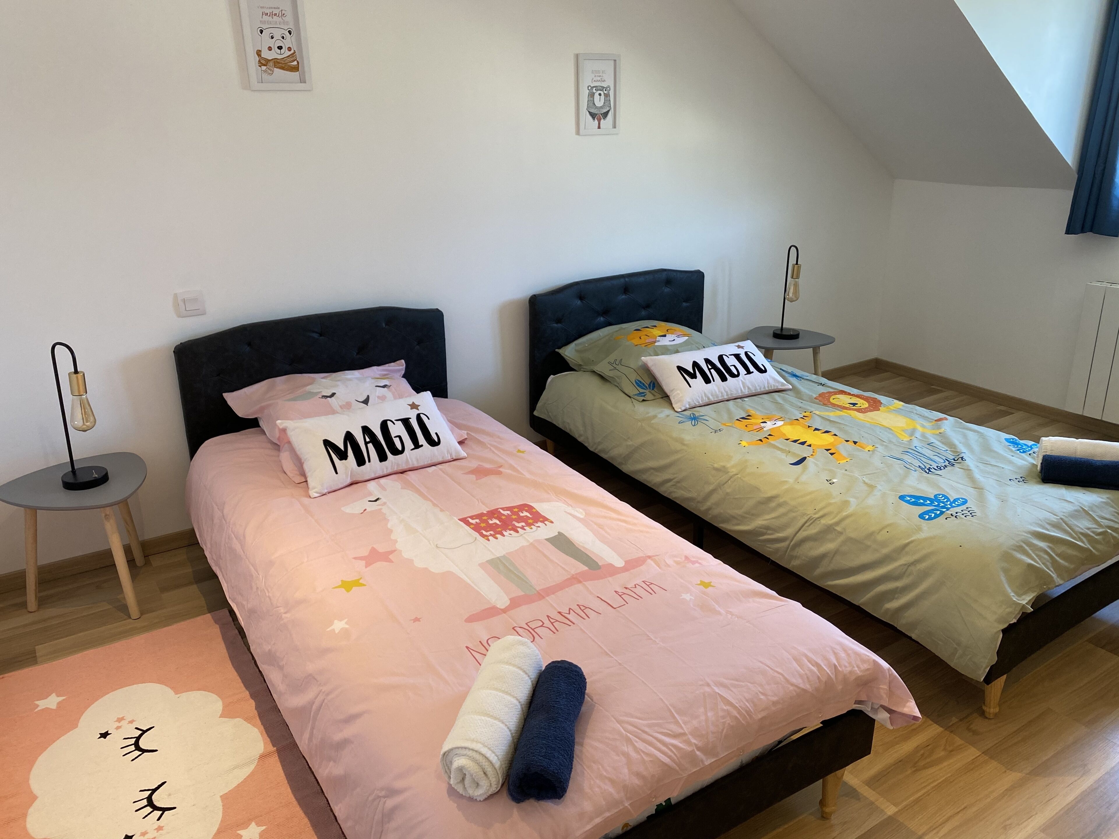 Two twin beds with distinct bedding, a small bedside table with a lamp, and a decorative wall piece.
