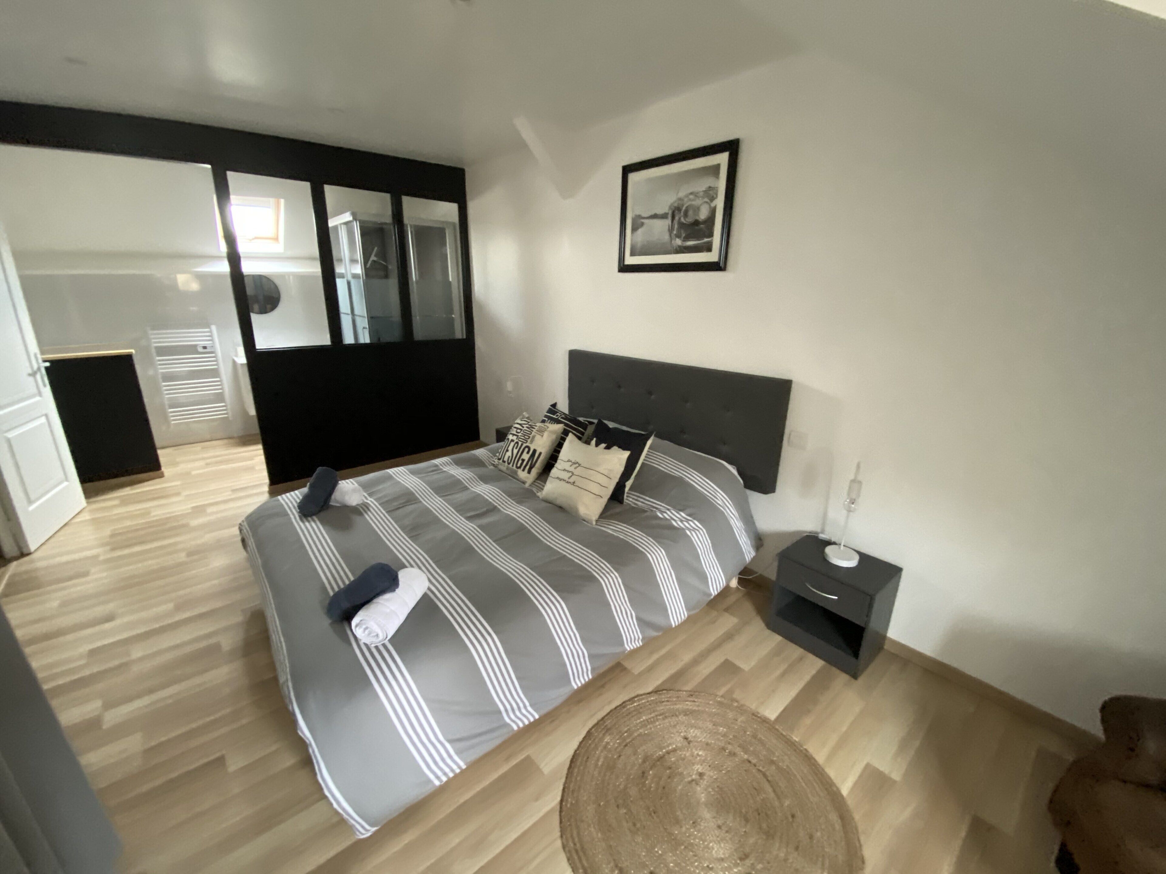 A modern bedroom with a bed, bedside table, and a mirror.