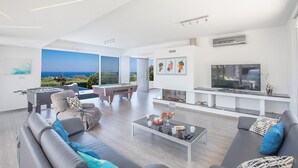 A modern living room with a pool table, sofa, and a large TV. - Protaras Seaview Villa Chloe (Protaras)