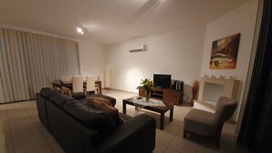 A living room with a sofa, a coffee table, a TV, and a fireplace. - Villa Imogine with Sea View (Neo Chorio)