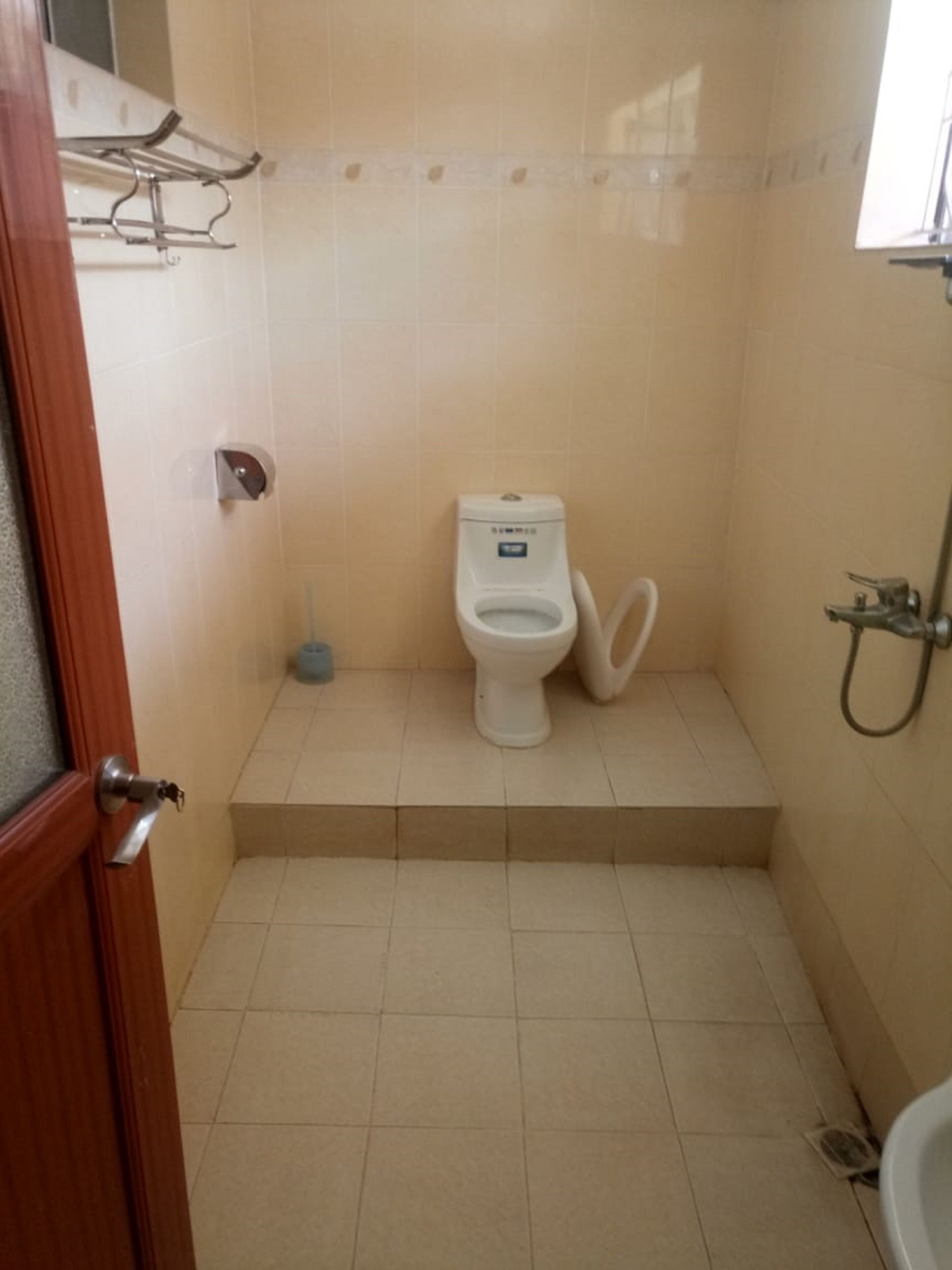 Une petite salle de bain comprenant des toilettes, une douche et un sèche-mains.