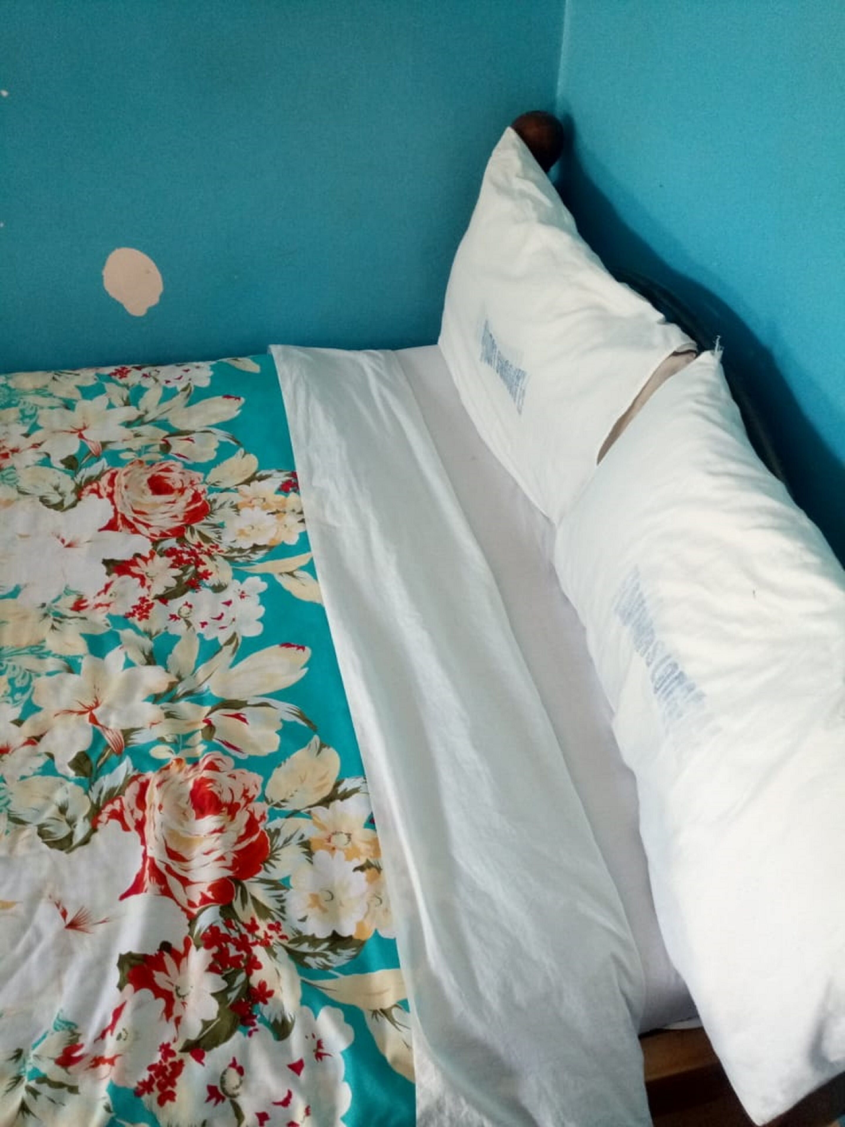 A bed with a floral bedspread and white pillows in a room with blue walls.