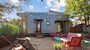 A deck with outdoor furniture, a house with a red door, and string lights. - The Local - 2 Blocks to Downtown Fay (Fayetteville)