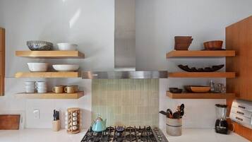 Een moderne keuken met houten planken, een gasfornuis en diverse keukengerei.