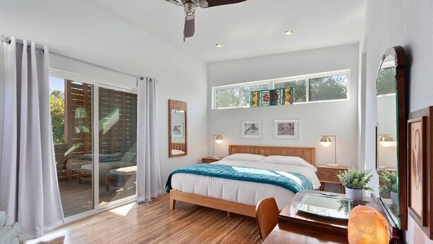 A modern bedroom with a large bed, sliding glass doors to a patio, and a ceiling fan. - The Local - 2 Blocks to Downtown Fay (Fayetteville)