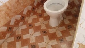 Un baño con inodoro, baldosas estampadas y una pared con diseño floral.