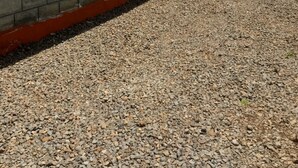 Un edificio con fachada de piedra y detalles en naranja, un camino de entrada de grava y una antena parabólica en el techo.