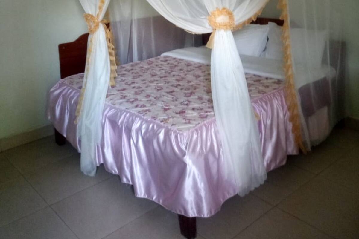A four-poster bed with a canopy, a floral bedspread, and a bedside table with a lamp.