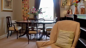 Un comedor con una mesa, sillas y un jarrón de flores.