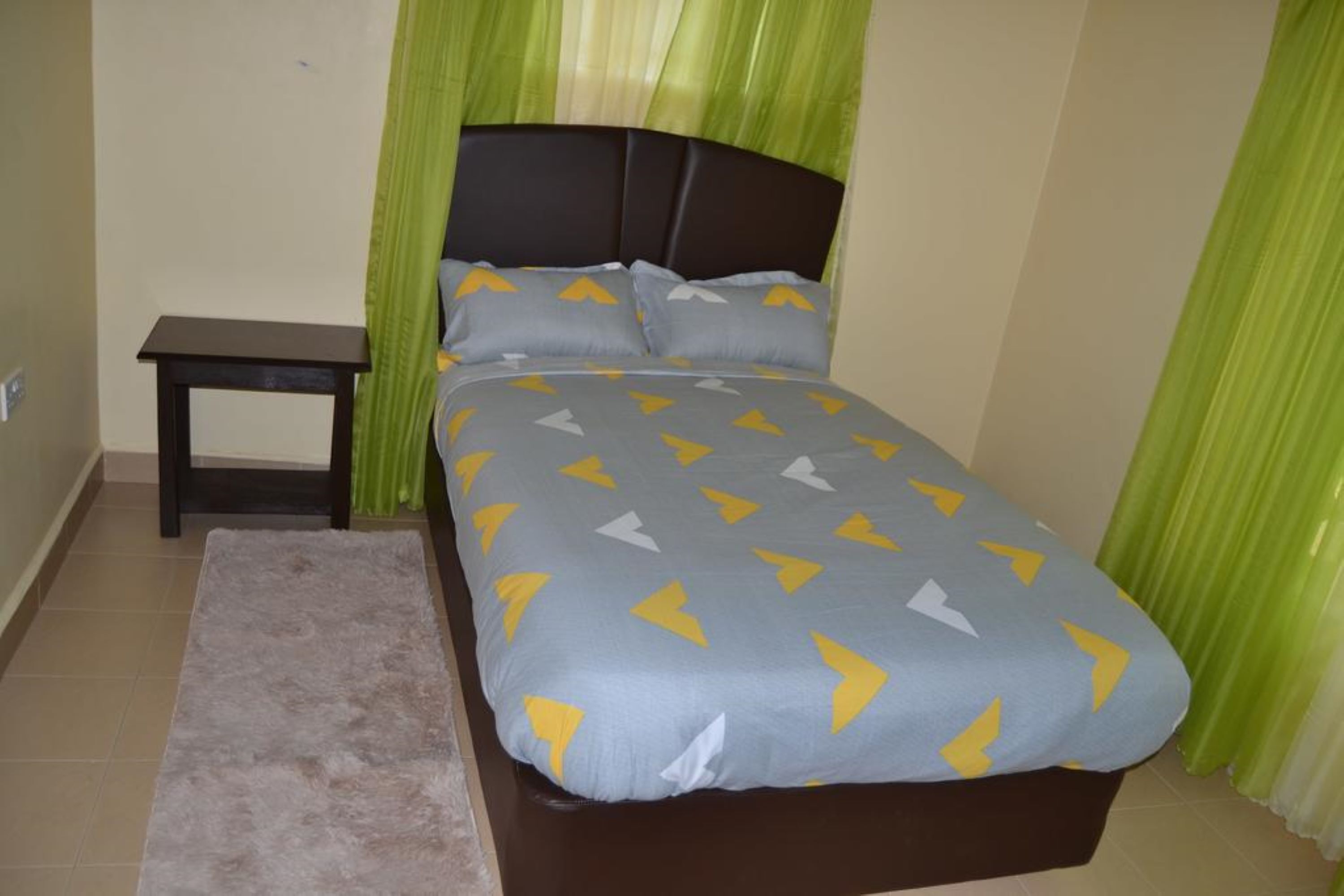 A bedroom with a bed, a nightstand, and a bench.