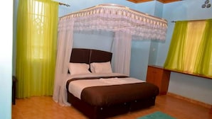 Une chambre à coucher avec un lit, un baldaquin, une table de chevet et une fenêtre avec des rideaux.
