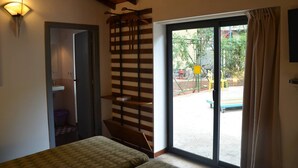 A bedroom with a bed, a wooden ceiling, a sliding glass door to an outdoor area, and a wall-mounted shelf. - Bungalow in an artistic villa (Mondello, Pa, Italy) beachfront, sea and city (Palermo)
