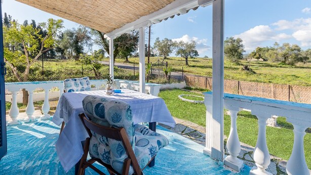 An outdoor seating area with a table and chairs, a pergola, and a view of a grassy landscape. - Blue House - Recently renovated (corfu)