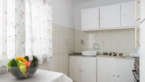 A kitchen with white cabinets, a sink, and a countertop. There is a bowl with fruits on the counter. - Blue House - Recently renovated (corfu)