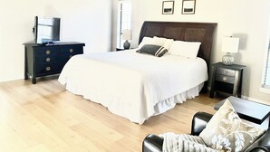 Een slaapkamer met een groot bed, een dressoir, een televisie en een plafondventilator.