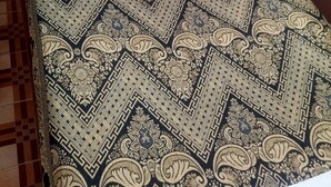 Tecido estampado com padrão geométrico e floral, provavelmente parte da decoração de um ambiente.