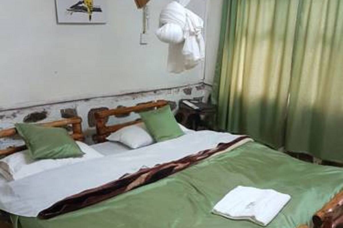A wooden bed with green bedding, a white pillow, and a green pillow on a wooden headboard.