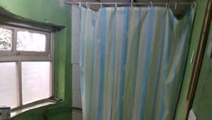 Ein kleines, schlichtes Badezimmer mit Toilette, Waschbecken und Duschvorhang.