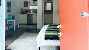 A compact room with a bed, a small table, and a kitchenette in the background. - Vintage Studio in Artsy, Modern Walkable Montrose Area! (Houston)