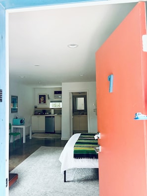 A compact room with a bed, a small table, and a kitchenette in the background. - Vintage Studio in Artsy, Modern Walkable Montrose Area! (Houston)