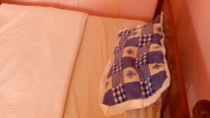A bed with a white sheet and a checkered blanket. - Migingo Lodge (Gilgil)