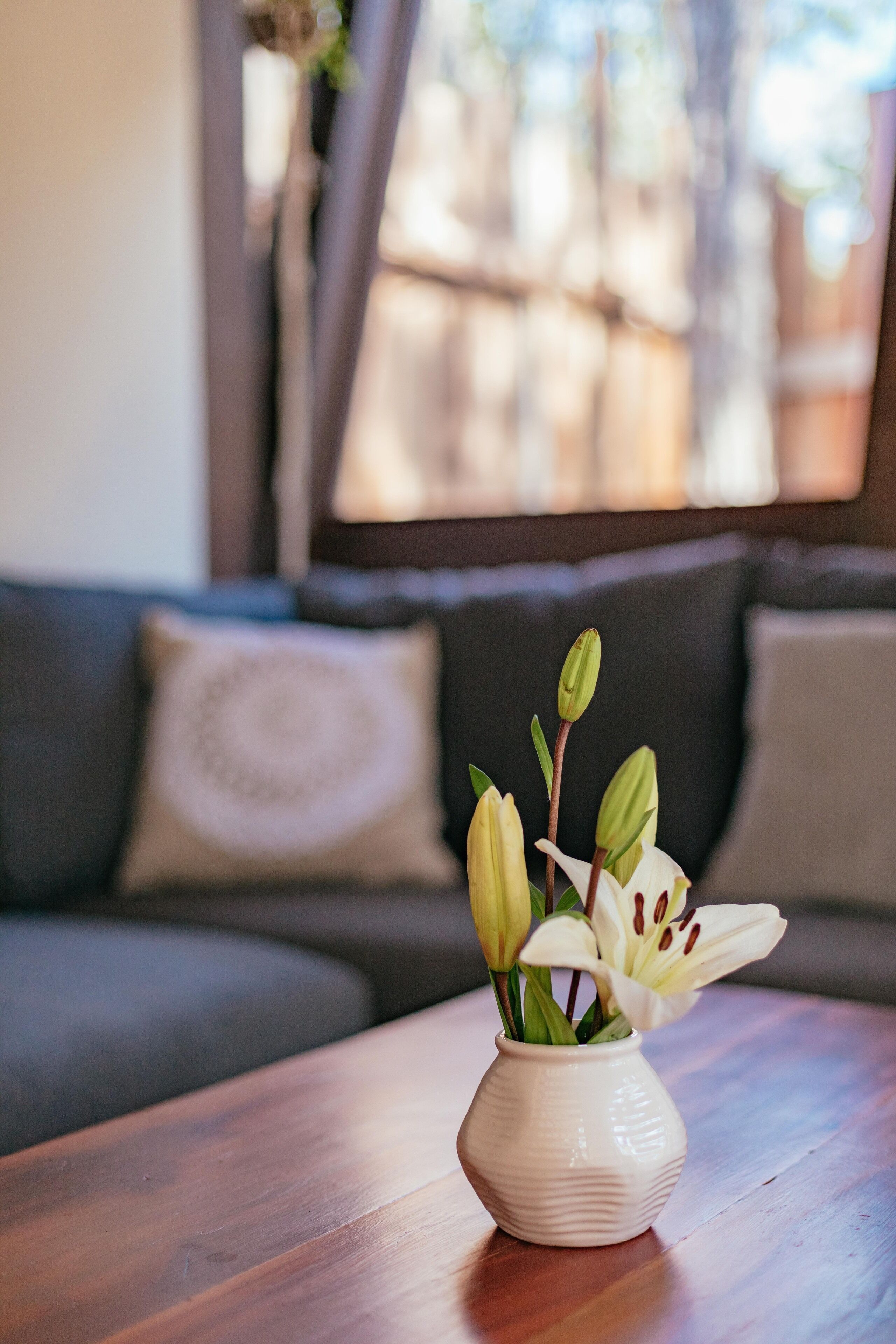A white vase with flowers on a wooden table.