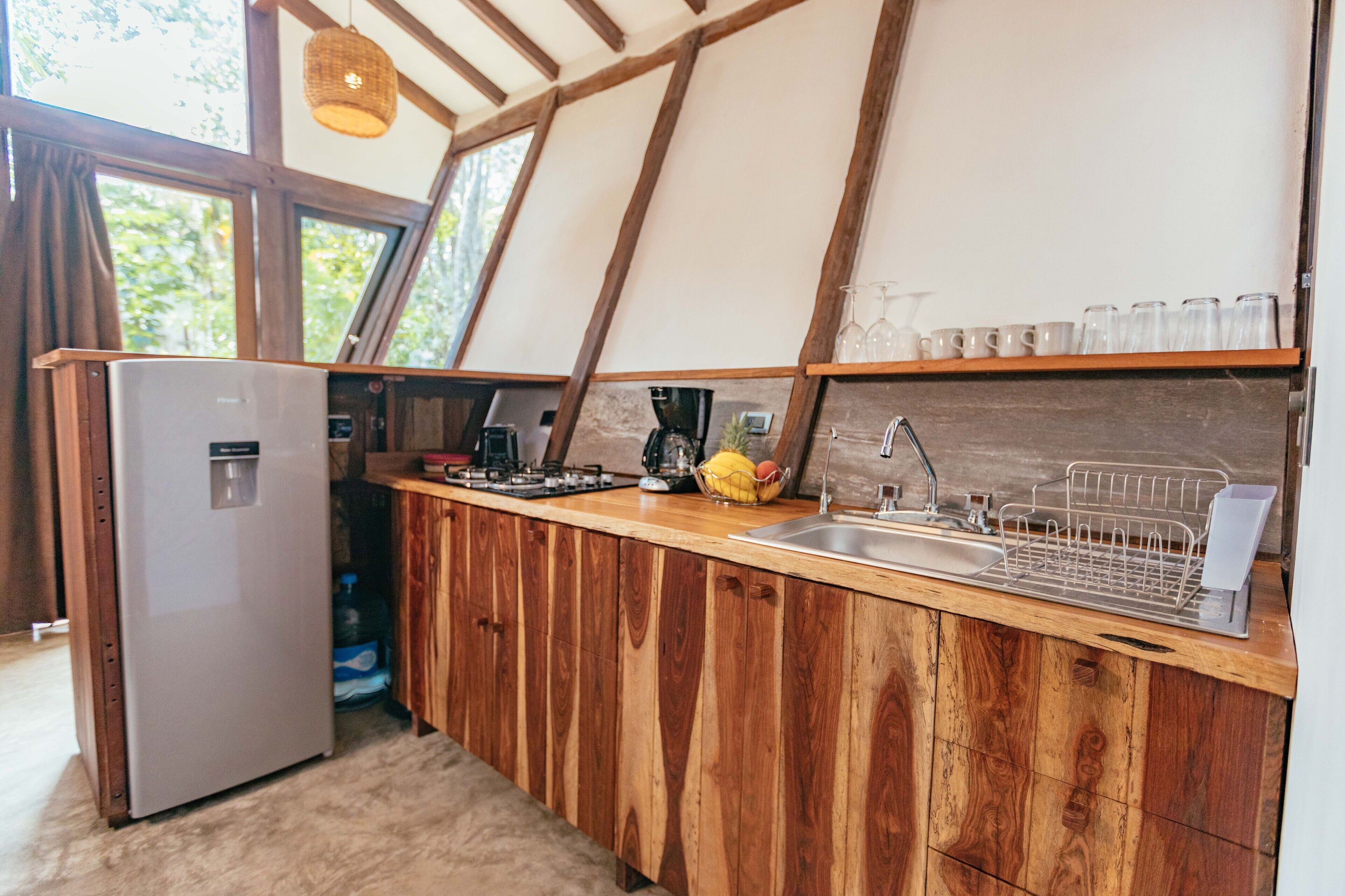 A compact kitchen with wooden cabinetry, a built-in sink, and a refrigerator.
