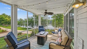A covered porch with wicker furniture, a ceiling fan, and string lights. - Bow-wow on The River #5 (Ottawa)
