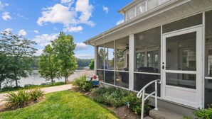 A building with a covered porch overlooking a lake, a grassy area, and a sign with a dog and a red circle. - Bow-wow on The River #5 (Ottawa)