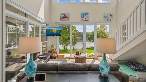 A spacious living area with a large window, a sofa, two lamps, and a TV. - Bow-wow on The River #5 (Ottawa)