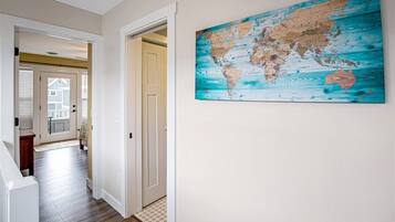 A hallway with a wooden floor, white walls, and a world map on the wall.