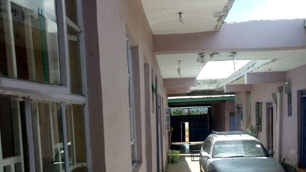 A covered corridor with a car parked at the end, leading to a gated entrance. - Rainbow Guest House (Gilgil)