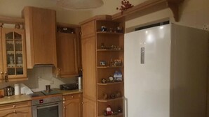 Een keuken met houten kastjes, een inbouwoven en een witte koelkast.