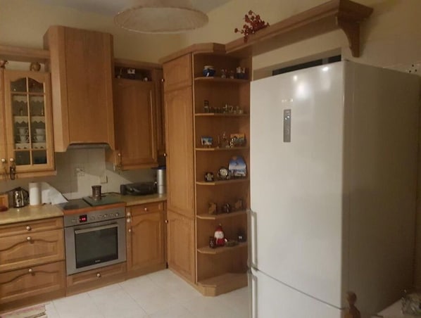 A kitchen with wooden cabinets, a built-in oven, and a white refrigerator.