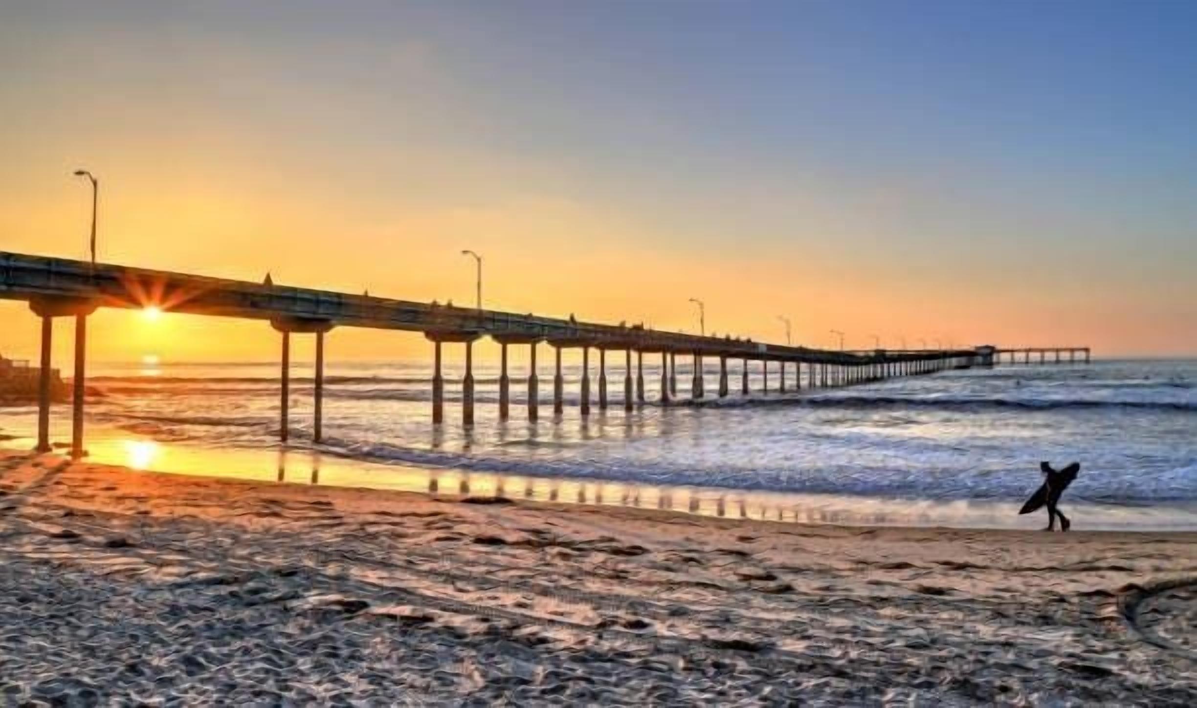 A pier extending into the ocean with a sunset in the background.