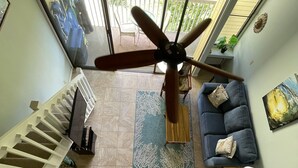 A spacious living area with a ceiling fan, a sofa, a coffee table, and a staircase.