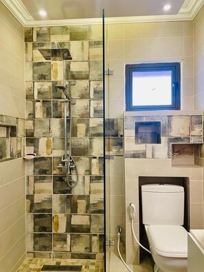 A bathroom with a shower enclosure, a toilet, and a small window. - Villa à 40metre de la mer à Flic en Flac   (Albion)