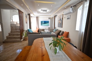 Una sala de estar moderna con una mesa de centro de madera, un sofá, un televisor y una escalera.