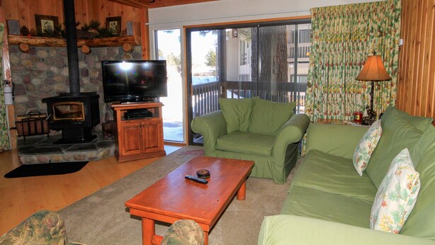 Una sala de estar acogedora con chimenea de piedra, televisor, sofá verde y una mesa de centro de madera.