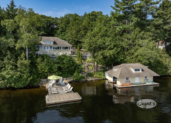 A lakeside property with a dock, a house, and a large tree. - Muskoka Paradise! Spacious & Inviting, Great Deck! Sleeps 16! Hot Tub! Bala! (Muskoka Lakes)