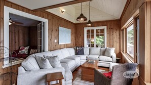 A cozy living room with a large sectional sofa, a small wooden coffee table, and a wicker chair. - Muskoka Paradise! Spacious & Inviting, Great Deck! Sleeps 16! Hot Tub! Bala! (Muskoka Lakes)