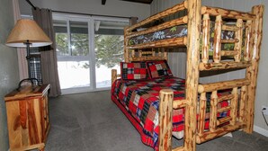 Una habitación con una cama litera de madera, una mesita de noche pequeña de madera y una lámpara.