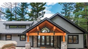 Une maison moderne avec des fondations en pierre, un porche en bois et un perron dallé de pierres.