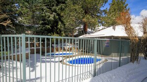 A fenced outdoor area with a swimming pool surrounded by snow. - Sierra Park Villas #24 (Mammoth Lakes)