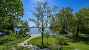 A pathway leading to a lake with a picnic area and a covered seating area.